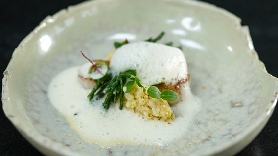 Jakobsmuscheln mit Zitrus-Beurre-blanc und Blumenkohlnocken auf einem rustikalen Teller angerichtet. © Joshua Stolz / solisTV 