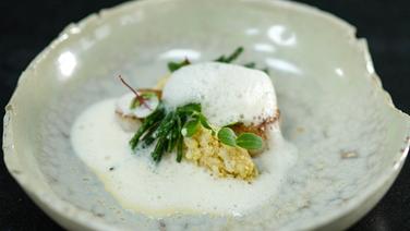 Scallops with citrus beurre blanc and cauliflower dumplings arranged on a rustic plate.  © Joshua Stolz / solisTV 