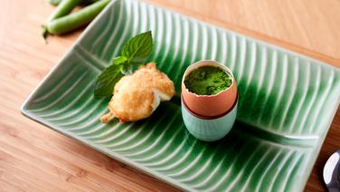 A fried onsen egg served alongside green peas on a rectangular plate with a leaf-like pattern.  © Joshua Stolz / solisTV 