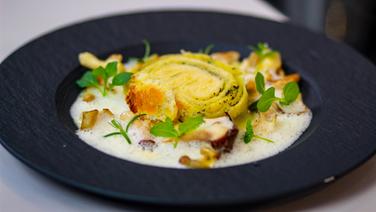 Stuffed Dampfnudel on a bed of mushrooms with whey cheese sauce served on a deep black plate.  © Sascha Kirchner / solisTV 