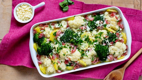 Brokkoli-Blumenkohl-Auflauf und ein Schälchen mit geriebenen Käse liegen auf einem Tisch. © NDR Foto: Claudia Timmann