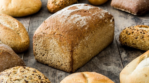 Ein frisch gebackenes Brot, umgeben von unterschiedlichen Brötchen. © photocase.de Foto: etorres69