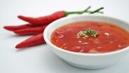Chilisoße in einem Schälchen. Daneben liegen frische Chilischoten. © fotolia Foto: sil007