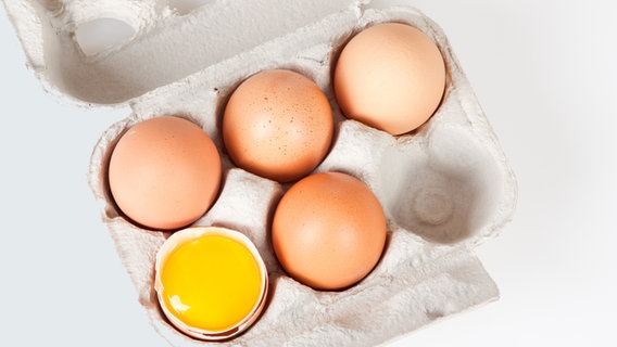 Ein Karton mit vier ganzen Eiern und einer Eischale mit Eigelb. © Fotolia Foto: Bernd Kröger