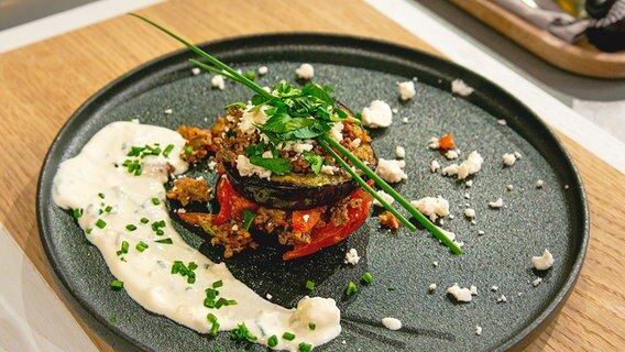 Auberginen-Schicht-Sandwich mit Schafskäse und Hackfleisch auf einem Teller angerichtet. © Fernsehmacher GmbH Foto: Norman Kalle