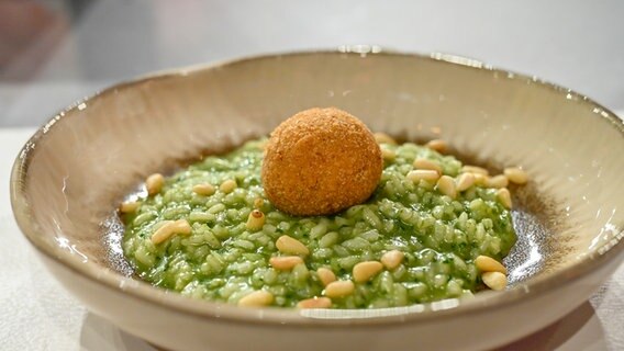 Basilikum-Risotto mit gebackener Ziegenfrischkäse-Praline in einem Suppenteller angerichtet. © NDR / Fernsehmacher GmbH Foto: Markus Hertrich