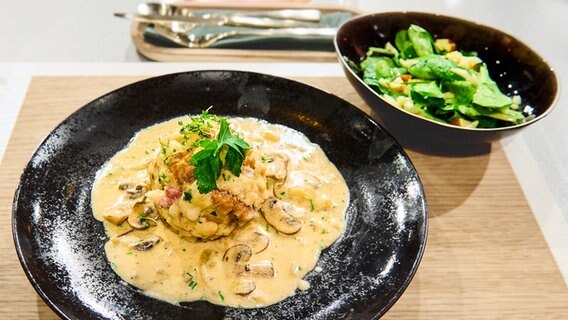 Brezen-Speckknödel mit Champignon-Rahmsoße auf einem Teller angerichtet. © NDR / Fernsehmacher GmbH Foto: Gunnar Nicolaus