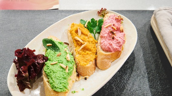 Crostini mit dreierlei Creme von Möhre, Erbse und Rote Bete auf einem Teller angerichtet. © NDR / Fernsehmacher GmbH Foto: Gunnar Nicolaus