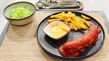 Currywurst mit Pommes frites und Mayonnaise auf einem Teller angerichtet. © NDR / Fernsehmacher GmbH Foto: Gunnar Nicolaus