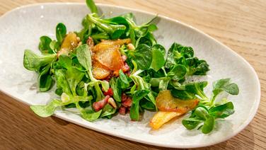 Lamb salad with bacon and caramelized apple slices placed on a plate.  © Fernsehmacher GmbH Photo: Norman Kalle