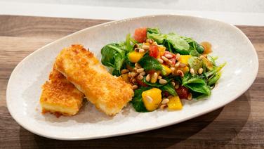 Paniertes Feta-Schnitzel mit Wassermelonen-Mango-Feldsalat auf einem Teller angerichtet. © NDR / Fernsehmacher GmbH Foto: Norman Kalle