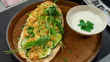 Zucchini-Flammkuchen mit Kräuter-Dip auf einem Teller serviert. © NDR Foto: Markus Hertrich