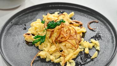 Schwäbische Käsespätzle mit gerösteten Zwiebeln und frittierter Petersilie auf einem Teller angerichtet. © NDR / Fernsehmacher GmbH Foto: Markus Hertrich