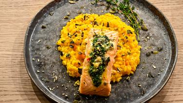 Kürbis-Risotto mit Knusperlachs auf einem Teller angerichtet. © Fernsehmacher GmbH Foto: Markus Hertrich