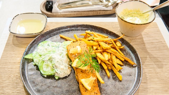 Lachsfilet mit frittierten Kartoffelstiften, Gurkensalat und Remoulade auf einem Teller angerichtet. © Fernsehmacher GmbH Foto: Gunnar Nicolaus