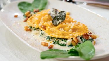 Selbst gemachte Tomaten-Ravioli mit Ziegenfrischkäse und Babyspinat-Soße auf einem Teller angerichtet. © NDR Foto: Markus Hertrich