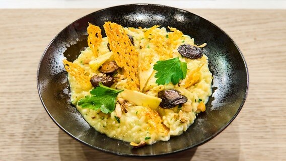 Risotto mit Kräuterseitlingen und Parmesanchip auf einem Teller angerichtet. © NDR / Die Fernsehmacher Foto:  Gunnar Nicolaus