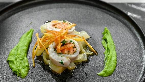 Schollen-Lachs-Röllchen mit Fenchelgemüse, Erbsenpüree und Kartoffelstroh auf einem Teller angerichtet. © NDR / Fernsehmacher GmbH Foto: Markus Hertrich