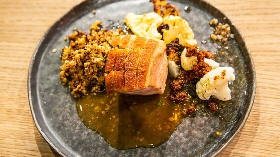 Schweinebauch mit Dreierlei vom Blumenkohl und Honig-Sojasauce auf einem Teller angerichtet. © Fernsehmacher GmbH Foto: Norman Kalle