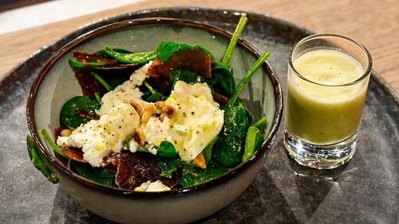 Babyspinat-Salat mit Bündnerfleisch und Fenchel-Kokos-Shot auf einem Teller angerichtet. © NDR/Fernsehmacher GmbH Foto: Markus Hertrich