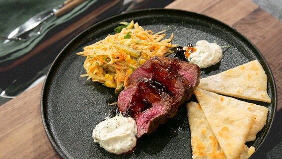 Teriyaki-Rumpsteak mit Pfannenbrot und Farmersalat auf einem Teller angerichtet. © NDR / Fernsehmacher GmbH Foto: Norman Kalle