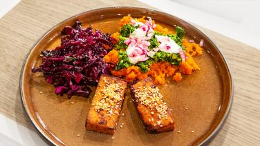 Teriyaki-Tofu mit Karottenstampf und Rotkohlsalat auf einem Teller angerichtet. © NDR / Die Fernsehmacher Foto: Norman Kalle