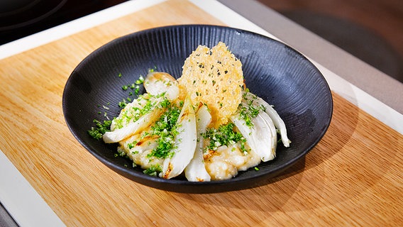 Wermut-Risotto mit dreierlei vom Fenchel und Parmesanhippe auf einem Teller serviert. © NDR/Fernsehmacher GmbH Foto: Norman Kalle