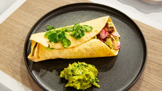 Wrap mit Huhn, Mole und Guacamole auf einem Teller angerichtet. © NDR / Die Fernsehmacher Foto: Norman Kalle