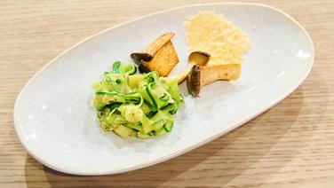 Zucchininudeln mit Kräuterseitlingen und Parmesanchip auf einem Teller angerichtet. © NDR / Fernsehmacher GmbH Foto: Gunnar Nicolaus