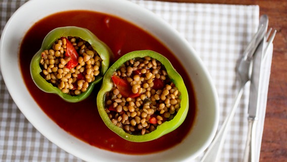 A casserole dish with two stuffed peppers is on the table.  © NDR Photo: Claudia Timmann