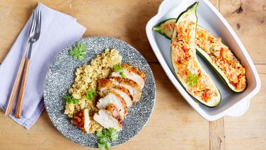 Ein Schüssel mit gefüllten Zucchini und ein Teller mit Hähnchen und Couscous stehen auf einem Tisch. © NDR Foto: Claudia Timmann