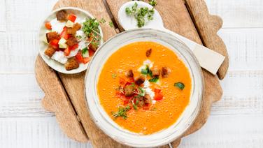 Ein Suppenteller mit gekühlter Gemüsesuppe mit Feta steht auf einem Brett. Daneben steht ein Tellerchen mit Croutons und Feta. © NDR Foto: Claudia Timmann