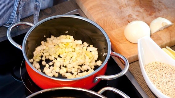 Zwiebeln und Knoblauch werden in einem Topf mit Butter angebraten © NDR Foto: Claudia Timmann