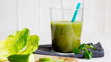 Ein Glas mit Gurken Ingwer Smoothie steht auf einem Tisch. Drumherum liegen vereinzelnd Salatblätter. © NDR Foto: Claudia Timmann