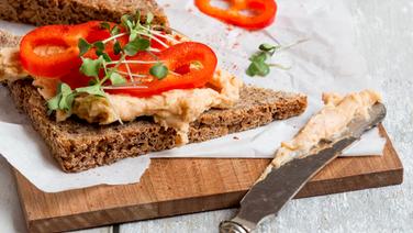 Brot mit Kichererbsenaufstrich liegt auf einem Holzbrett. © NDR Foto: Claudia Timmann