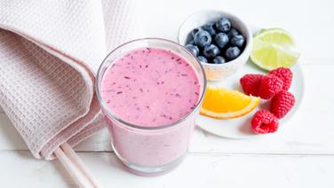 Ein Glas mit Kokos-Beeren-Smoothie steht auf einem Tisch. Daneben liegt ein Teller Obst. © NDR Foto: Claudia Timmann