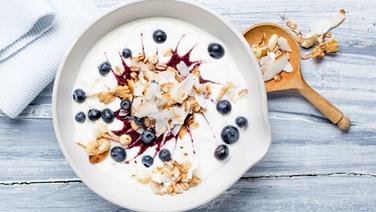 Eine Schüssel mit Kokosjoghurt mit Blaubeeren und Nüssen steht auf dem Tisch. © NDR Foto: Claudia Timmann