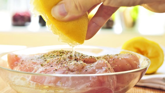 Hähnchenfleisch wird in einer Glasschüssel mit Zitronensaft und Gewürzen mariniert. © imago/Panthermedia Foto: Elenathewise