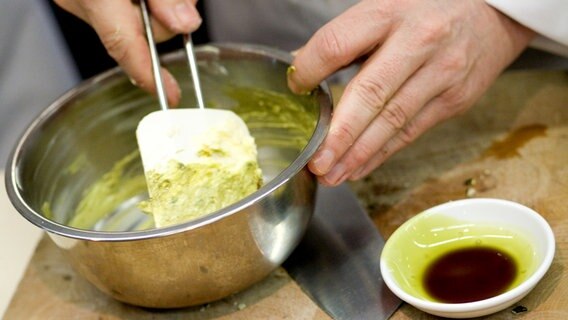Johann Lafer vermischt in einem Topf Butter mit Kürbiskernöl an © NDR Foto: Claudia Timmann
