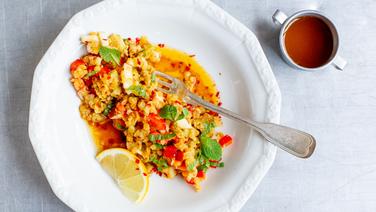 A plate of lentil salad and a bowl of dressing are on the table.  © NDR Photo: Claudia Timmann