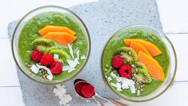 Zwei Schüsseln mit grünem Löffelsmoothie mit Papaya, Himbeeren und Kiwischeiben stehen auf dem Tisch. © NDR Foto: Claudia Timmann