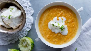 There is a soup bowl with carrot and ginger soup and a bowl with lime cream on the table.  © NDR photo: Claudia Timman