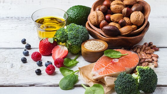 Salmon, vegetables, nuts, berries and oil on wooden table.  © fotolia.com Photo: aamulya