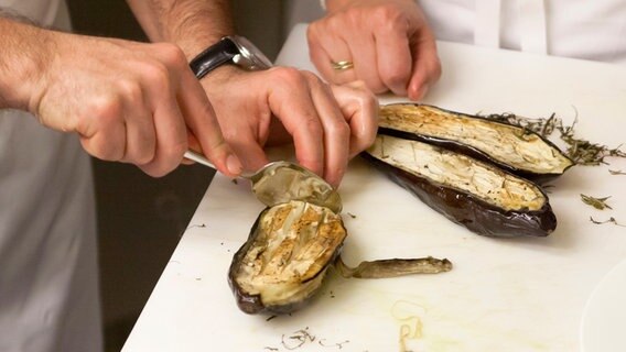 Ali Güngörmüs löst gebackenes Auberginenfleisch von der Schale. © NDR Foto: Claudia Timmann