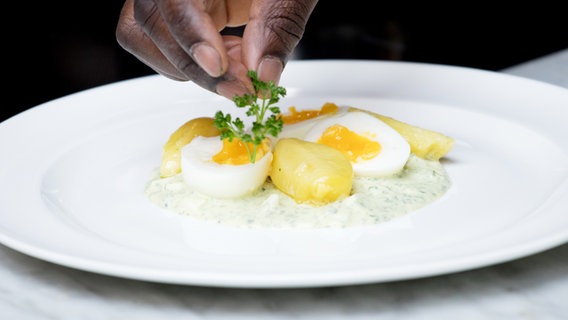 Frankfurter Grüne Soße mit Pellkartoffeln und wachsweich gekochten Eiern werden auf einem Teller angerichtet. © NDR Foto: Claudia Timmann