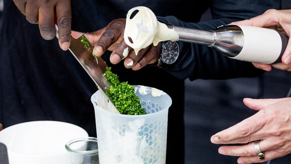 Gehackte Kräuter werden in ein Gefäß mit einem Stabmixer gegeben. © NDR Foto: Claudia Timmann