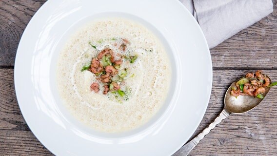 Ein Teller Kartoffelsuppe mit Krabben auf einem Holztisch. © NDR Foto: Claudia Timmann