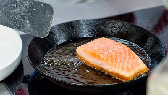 Ein Stück Lachsfilet brät in einer gusseisernen Pfanne. © NDR Foto: Claudia Timmann