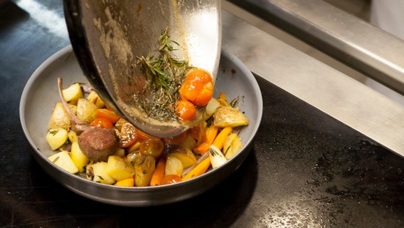 Tomaten und Rosmarin werden aus einer Pfanne zum Ofengemüse gegeben. © NDR Foto: Claudia Timmann