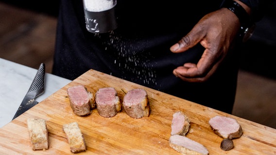In Scheiben geschnittenes Lammfleisch wird mit etwas Meersalz gewürzt. © NDR Foto: Claudia Timmann